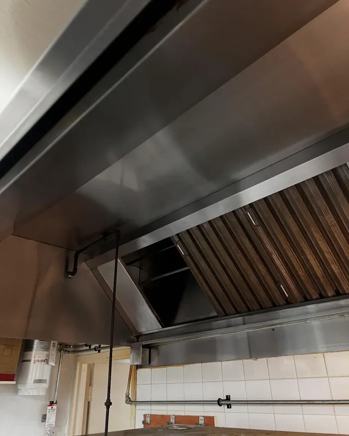 A kitchen hood with clean stainless steel and baffle filters after cleaning